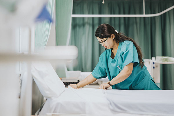 Female nurse making hospital bed