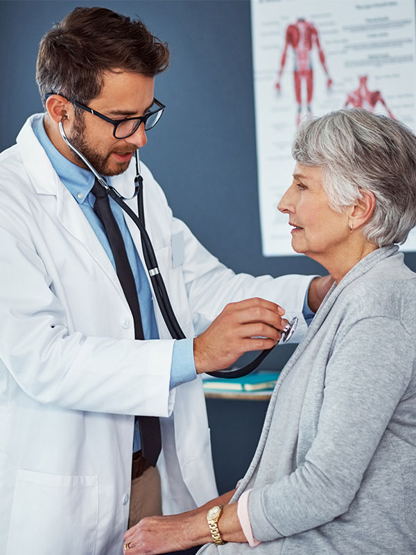 Male doctor with female patient listening to heart with stethoscope