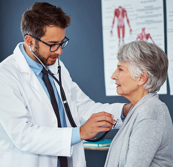 Male doctor with female patient listening to heart with stethoscope