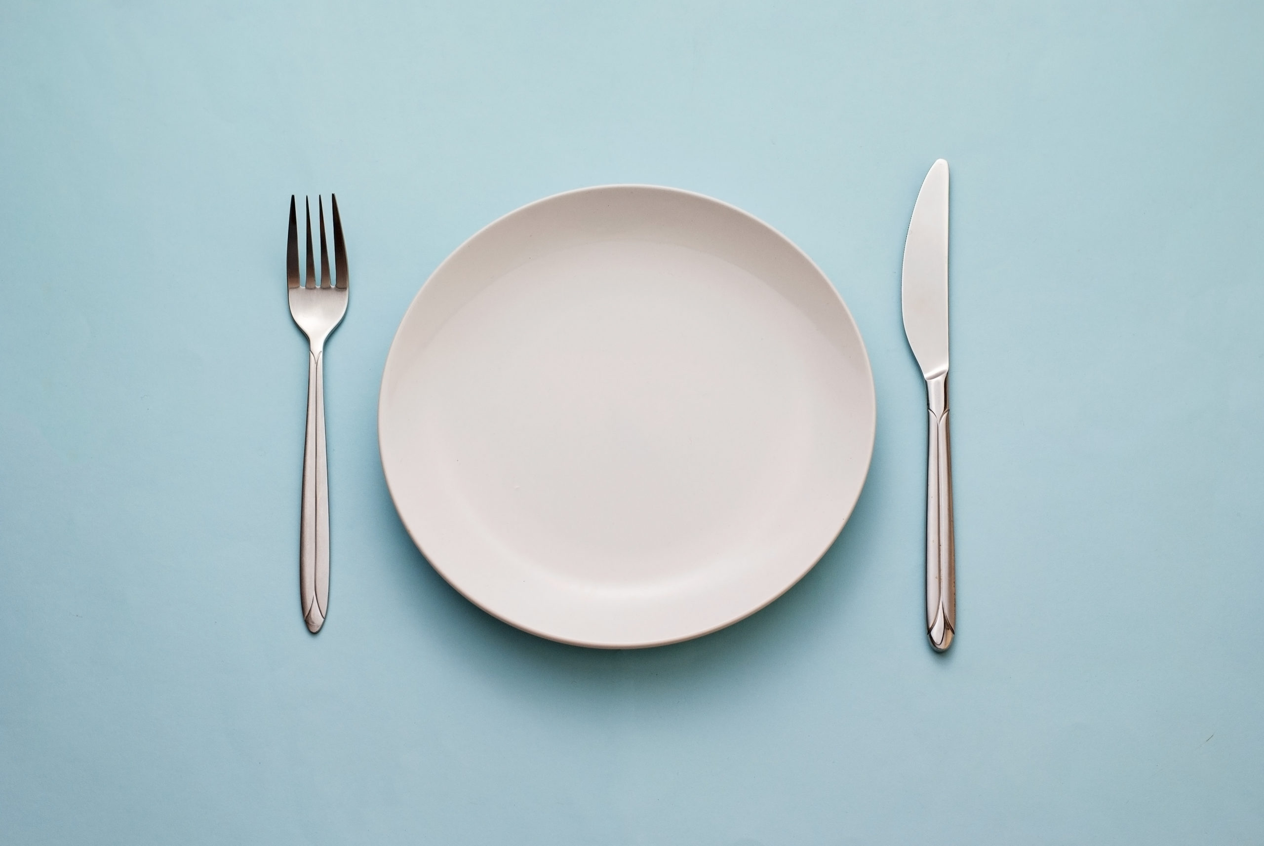 white plate on blue table with fork and knife