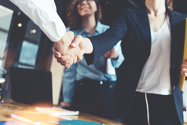 Business women on the right shaking hands with man on the left