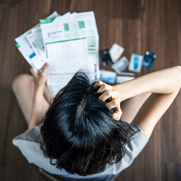 Top view of woman sitting on the floor reviewing medical bills