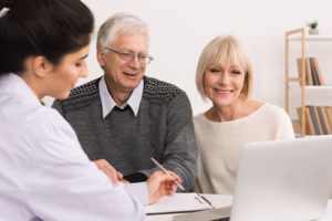 Elderly couple viewing laptop with female doctor