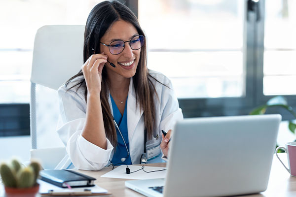 Female doctor sitting at desk speaking on video call