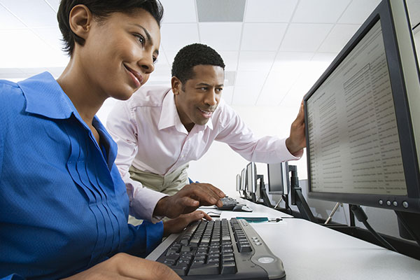 Man and women looking at computer screen with data on display