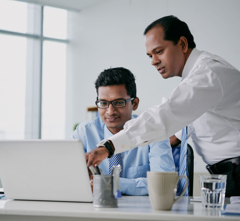 two businessmen looking together at a computer at a desk