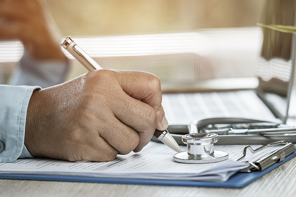 doctor writing on clipboard