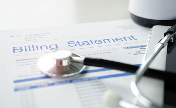 Medical billing statement on a table with stethoscope and tablet