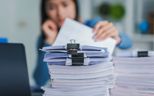 women at a desk with piles of papers