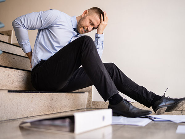 Man sitting on stairs while rubbing his hurt back