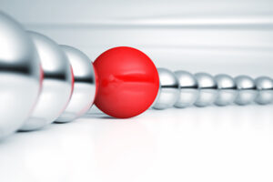 row of silver balls with one red ball among them