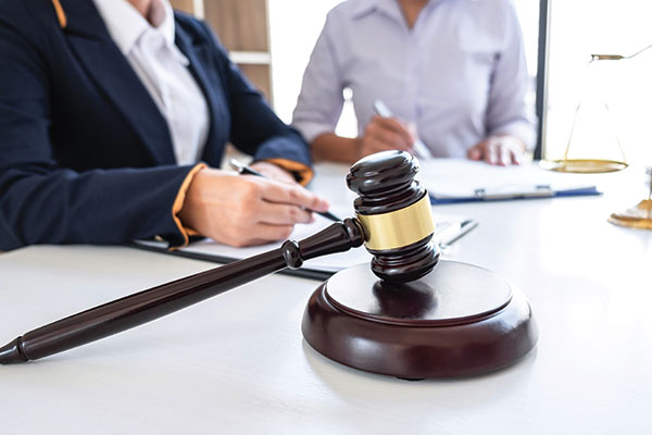 Judge's gavel on a table with two business women working in the background