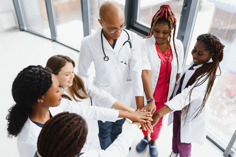 Group of medical professionals standing together in a circle putting their hand together